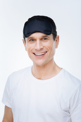 I need to rest. Nice positive joyful man smiling and looking at you while preparing to sleep