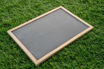 Abstract chalk blackboard with wood border frame on grass floor included copyspace ready used as background for add text or graphic