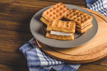 waffles with cream on plate on wooden table.