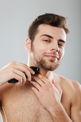 Picture of good-looking adult guy doing hygiene and health procedure with shaving his bristle using...
