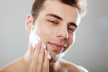 Close up portrait of a smiling man applying shaving foam