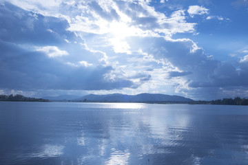 A blue lake with bright sunshine and a blue sky with white clouds.