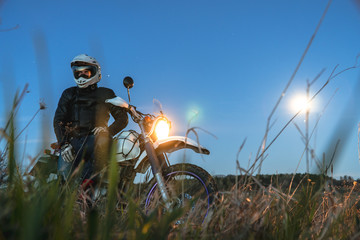 Active way of life, enduro motorcycle, a guy looks at the stars at night and the moon, unity with...