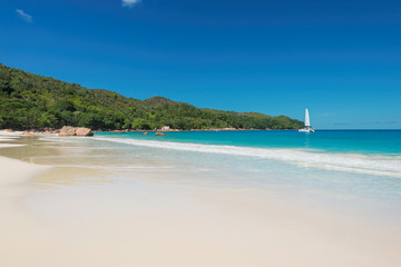 Fototapeta na wymiar Paradise Anse Lazio beach at Praslin island and sailboat on horizon, Seychelles.