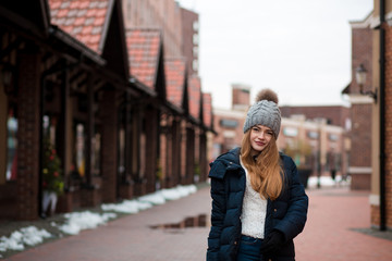 Cool blonde woman wearing black winter coat and knitted hat posing at the street in Kiev