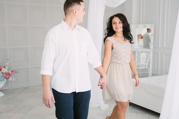 Fototapeta premium Young cheerful european couple in love embracing and kissing in decorated studio, light pastel colors, dating.