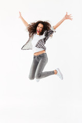 Full length image of Cheerful curly woman jumping in studio