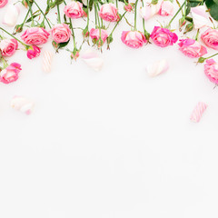 Floral frame of pink roses and marshmallow on white background. Flat lay, Top view.