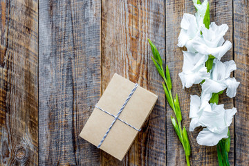 Gift box wrapped in craft paper near flower gladiolus on rustic 