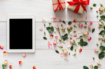 Tablet screen with copy space on white wood with rose flowers heart and gift boxes