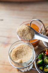 Thai style Seasoning, fish sauce, sugar, vinegar and chilli powder in glasses and aluminium cover on wooden brown table, street food restaurant