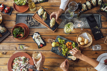 Overhead view of vegetarian food on table and peoples hands