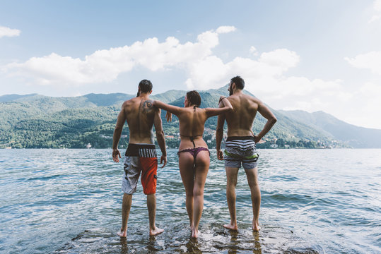 Rear view of three young adult friends standing in lake Como, Como, Lombardy, Italy