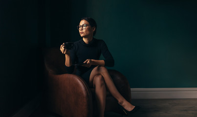 Businesswoman sitting on chair and having coffee