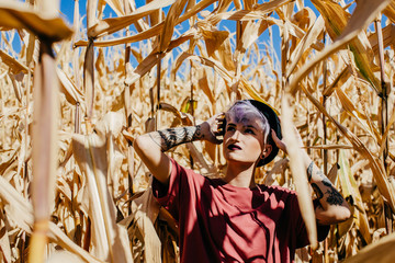 .Young tattooed woman between a corn field on a sunny day. Free spirit, good mood. Lifestyle