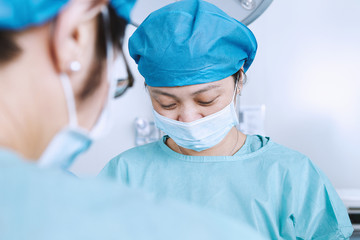 Over shoulder view of female surgeon performing operation in maternity ward operating theatre