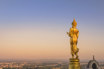 Fototapeta premium public big golden buddha statue standing in Wat Phra That Kao Noi located on mountain at Nan province Thailand in sunset