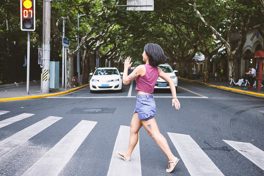 Woman marching across pedestrian crossing, Shanghai French Concession, Shanghai, China