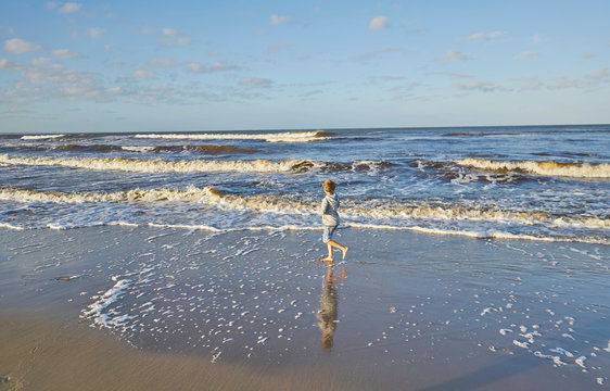 Boy in beach playing in lapping waves, Polonio, Rocha, Uruguay, South America