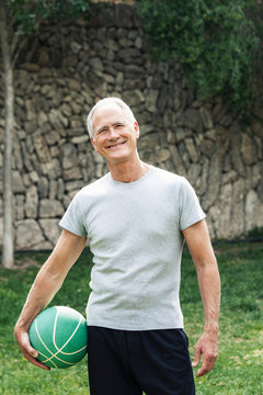 Portrait of man holding basketball looking at camera smiling