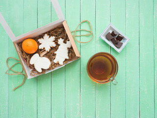 Glass cup of black tea, chocolate and gingerbread gingerbread on a mint-colored table