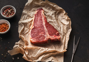 Raw t-bone steak on craft papper on dark background