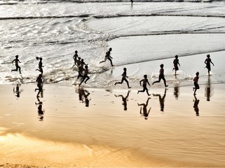 Fototapeta na wymiar Water reflection of running kids on the beach in Biarritz, Côte des Basques, France