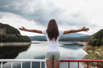 Woman with arms open by safety barrier by lake, Koralat, Zagrebacka, Croatia