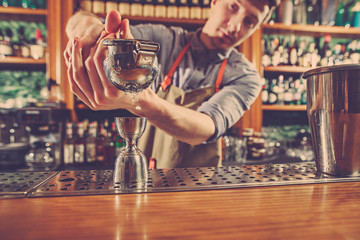 Expert barman is making cocktail at night club.