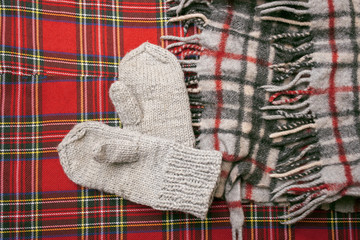 Warm woolen scarf and mittens on a red background