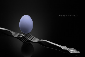 Happy Easter, violet egg two forks ancient silver on a black background.