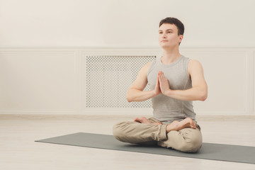 Fototapeta na wymiar Young man practicing yoga sitting in padmasana