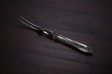 Fork for meat on wooden background.
