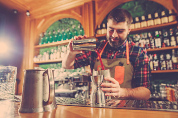 Barman making an alcoholic cocktail at the bar counter on the bar background