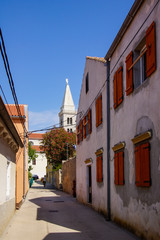 Fototapeta na wymiar Houses with red windows in a small alley in Croatia