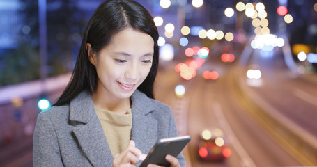 Woman look at mobile phone with traffic background