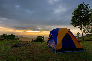 Tourist and tent in camp among meadow in the mountain at sunrise