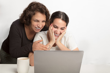 Two women laughing at something on a laptop