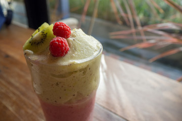 A glass of raspberry smoothie with fresh raspberries