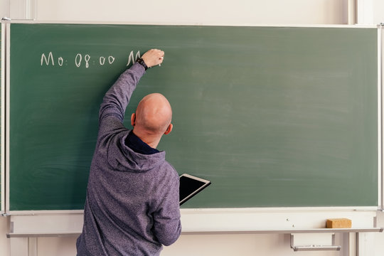Rear view of a teacher writing on the greenboard