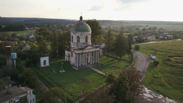 Aerial survey of a medieval christian church with roman inscription and statues on a roof in ukrainian village Pidhirtsi (4K, 25fps)
