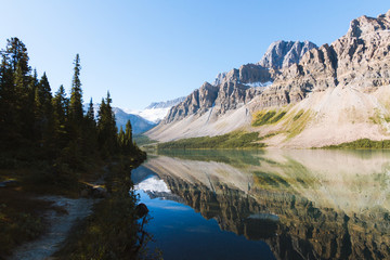 Reflection of Rocky Mountains in Bow Lake in Canada on sunny day with clear sky