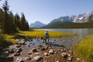 Man near Waterfowl Lakes surronded by Rocky Mountains on sunny day
