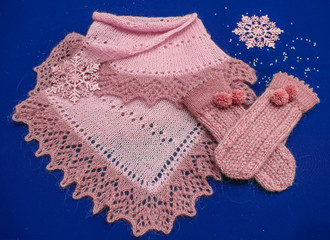 Knitted shawl and gloves on blue background