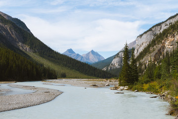 Scenic remote wide valley with river and forest in Rocky Mountains in Canada on cloudy day