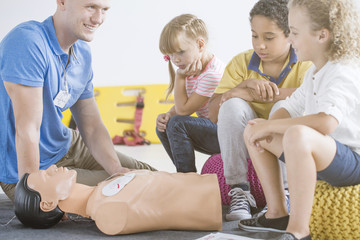 Paramedic showing defibrillator on manikin - obrazy, fototapety, plakaty