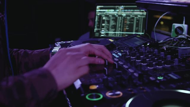 Close up of dj playing party music on modern cd usb player in disco club - Nightlife and entertainment concept - Defocused background with shallow depth of field and focus on buttons near mixing hand