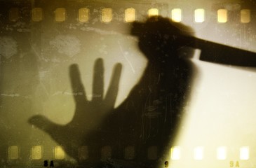 Vintage sepia film strip with hand and knife. Crime concept.