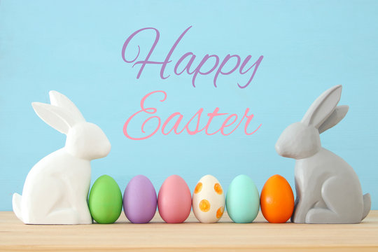 Cute bunny next to easter colorful eggs over colorful background.