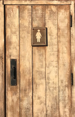 Woman rest room sign on old wooden door